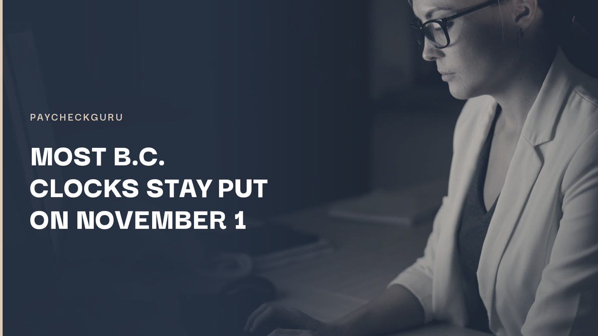 Woman in glasses and a white blazer typing at a desk in a dark office at night, illustrating payroll checks for B.C. staying on permanent daylight saving time.